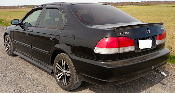 Acura EL 1999 showing rear spoiler on rear deck lid, vinyl gutter side skirt added to OEM side skirt. Window's rain deflector is an aerodynamics mistake.