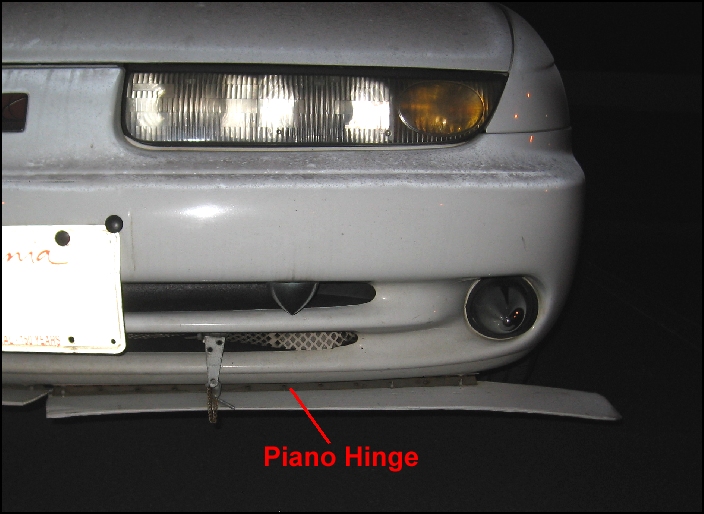 Air dam is in two parts.  Each side is attached using a piano hinge to block any air and allow for a stable relationship of the dam to the oncoming air.  One spring and one chain do the rest.