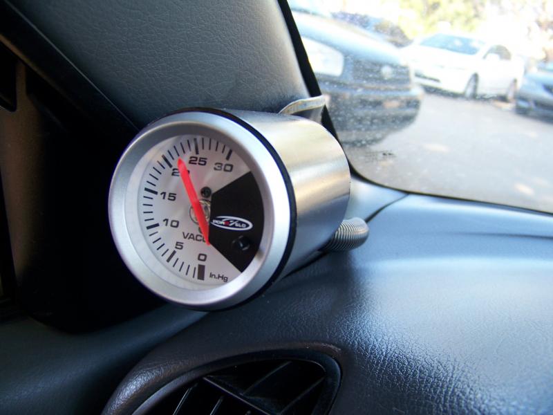 This gauge pod is custom made with a 2 1/16" inner diameter conduit PVC pipe, because it was hard to find a single gauge pod. The PVC pipe is cut to fit, then heat bended and finally painted. It is attached with 2 screws.

I had to put a screw inside the vacuum hose that goes from the manifold to the gauge to control the needle vibrations. It act as a restriction and buffers out any pulsating movements.