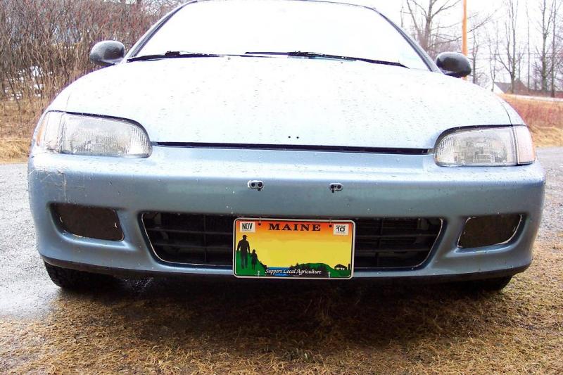 Zipties hold pieces of recycled plexi covering a hole that was previously cut in the bumper.  Licence plate was lowered to partially obscure the opening.